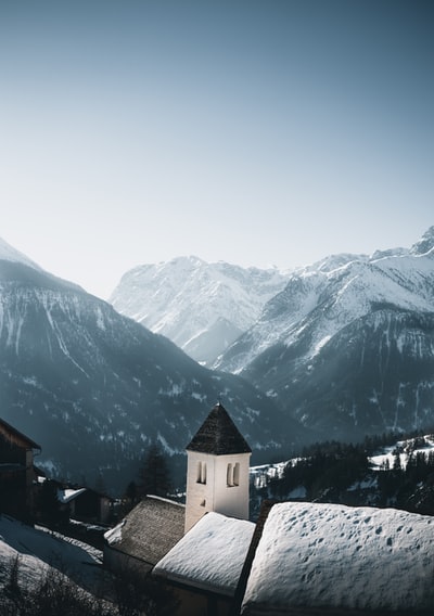 白天，雪山附近的雪地上有白色和棕色的混凝土建筑